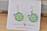 Round silver-tone earrings with green and mint chevron pattern on white display card