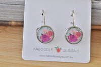 Round silver-tone dangle earrings with pink and magenta boho floral print, on Kaboodle card