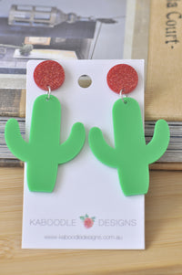 Green perspex cactus drop earrings with red glitter stud tops on Kaboodle Designs card