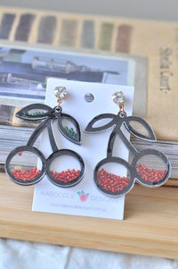 Pair of black cherry-shaped earrings with red and green bead fill, on jewellery card