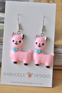 Pink resin llama drop earrings with mint bandana detail on Kaboodle card