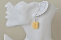 Close-up of ramen noodle earring worn on ear showing crinkled texture