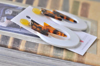 Angled view of lightning bolt earrings showing yellow stud and gold-tone connector