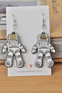 Pair of acrylic astronaut drop earrings with mirrored gold visors on Kaboodle Designs card