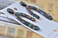 Close-up angled view of horseshoe earrings highlighting speckled multicolour pattern