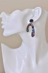 Single horseshoe earring worn on ear mannequin showing black stud and drop