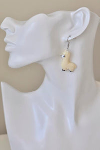 Single beige llama earring worn on a model's ear, close-up side view