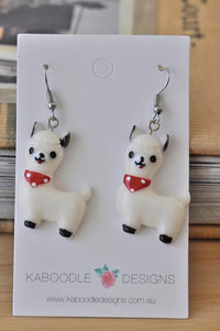 White resin llama drop earrings with red polka-dot scarves on Kaboodle Designs card