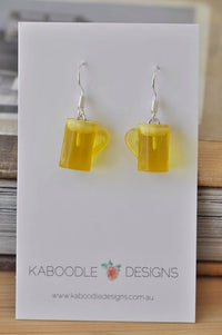 Pair of yellow resin beer jug earrings on Kaboodle Designs card with silver hooks