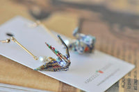 Close-up of folded paper crane earring showing floral patterned paper detail