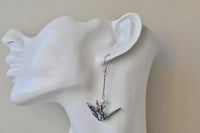 Origami crane earring worn on ear, shown against neck for scale