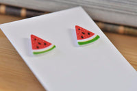 Close-up of watermelon stud earrings on white card showing seed and rind detail