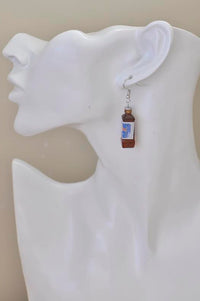 Single energy drink bottle earring worn on ear, side view against white mannequin