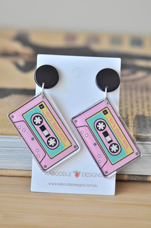 Pair of pink cassette tape dangle earrings with black round tops displayed on a Kaboodle Designs card