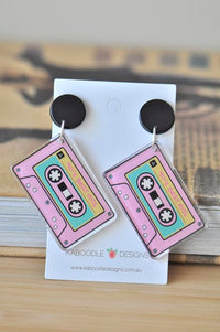 Pair of pink cassette tape dangle earrings with black round tops displayed on a Kaboodle Designs card