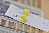 Pair of lemon earrings resting on Kaboodle backing card atop books