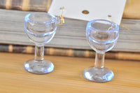 Close-up of two clear wine glass earrings standing upright showing stem and base detail