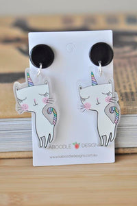 Acrylic rainbow cat unicorn drop earrings with black studs on white card backing