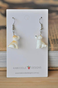 Pair of resin puppy dangle earrings on a Kaboodle Designs card, front view