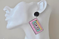 Cassette tape dangle earring worn on a model's ear, showing the black top and hanging cassette charm