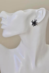 Close-up of black spider stud earring worn on a model's ear