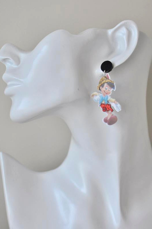Pinocchio dangle earring shown worn on an ear model, hanging from a black stud