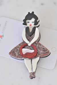 Acrylic retro lady brooch with glittery bronze dress and red handbag, front view