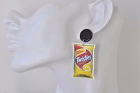 Twisties Cheese packet earring shown worn on a model's ear, hanging from a black stud