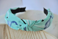 Mint flamingo print knotted headband shown from above against wooden surface