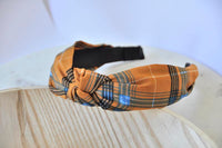 Fabric knotted headband in mustard chequered stripe with black, navy and blue check pattern, shown flat