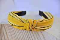 Close-up of knotted mustard headband showing black and white stripe detail