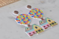 Close-up of two balloon house earrings laid flat, showing perspex finish and colour detail