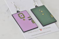 Angled view of both mismatched door earrings showing enamel detail and doorknobs