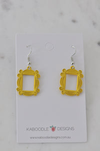 Pair of yellow scroll-edged frame earrings on a Kaboodle Designs card