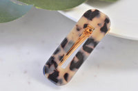 Rectangular acrylic barrette in cream and black leopard print, angled front view