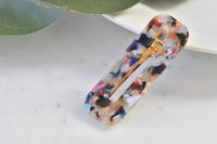 Speckled multicolour acrylic rectangular barrette with gold clasp, angled view