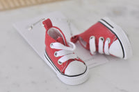Close-up of red high-top sneaker earring showing laces, eyelets and white sole