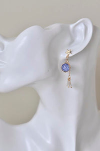 Blue-violet galaxy stone earring with crystal and gold drop details, shown worn on ear
