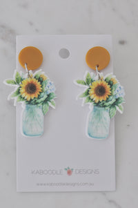 Pair of acrylic sunflower in a jar drop earrings on mustard yellow studs, on Kaboodle Designs card
