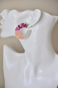 Close-up of marbled acrylic hoop earring worn on ear, showing gold-tone stud detail