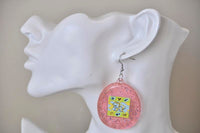 Single pink Tamagotchi earring worn on ear, side view against neutral background