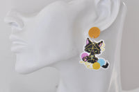 Yarn-tangled kitten earring with pink, blue and yellow wool balls shown worn on ear