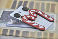 Close-up angled view of red glitter candy cane earrings showing layered perspex finish