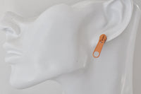 Close-up of orange zip stud earring worn on a display ear model