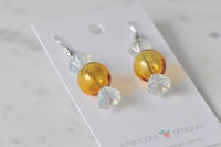 Pair of lolly-shaped drop earrings laid flat on backing card