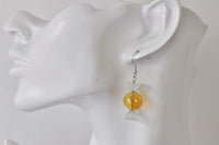 Candy lolly earring shown worn on ear, close-up side view