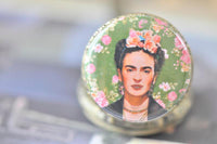 Close-up of Frida Kahlo illustration with pink roses on pocket watch pendant