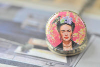 Close-up of Frida Kahlo pocket watch pendant showing floral crown and pink patterned backdrop