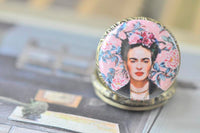 Close-up of Frida Kahlo pocket watch pendant with pink floral artwork detail