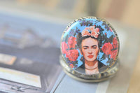 Close-up of Frida Kahlo artwork on pocket watch pendant with roses and floral crown detail
